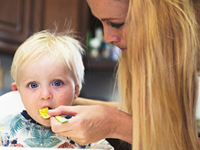 Мама годує маленьку дитину Мама годує маленьку дитину